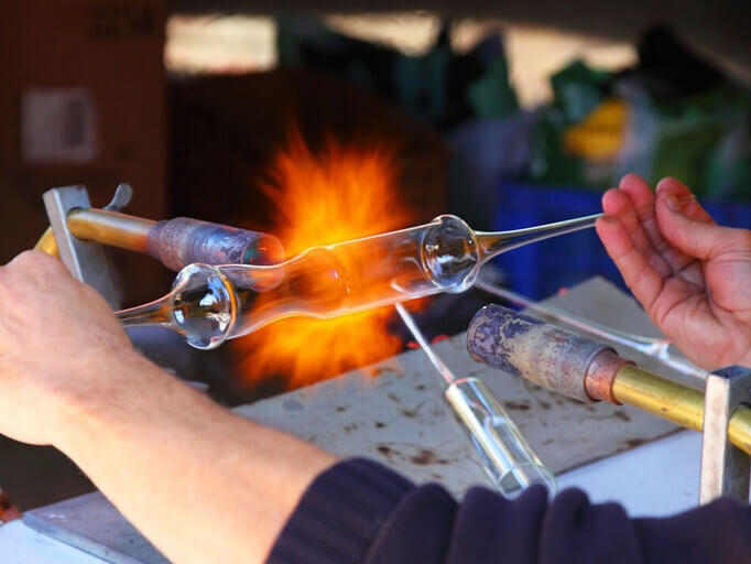 Un artisan travaillant sur un objet en verre soufflé dans son atelier